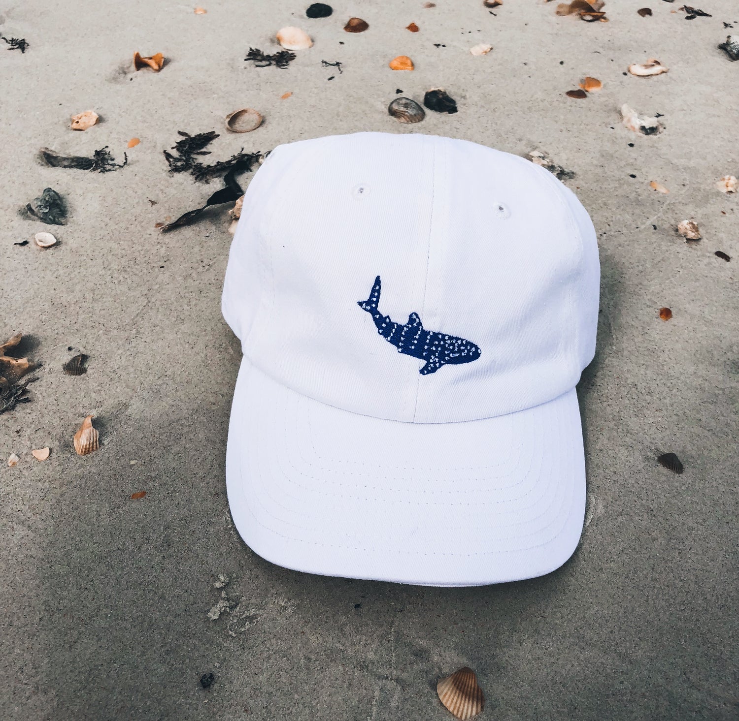 Connected Clothing Company Whale Shark Embroidered Cotton Cap on a beach - 10% of profits donated to Mission Blue ocean conservation efforts - ethically and sustainably made clothing