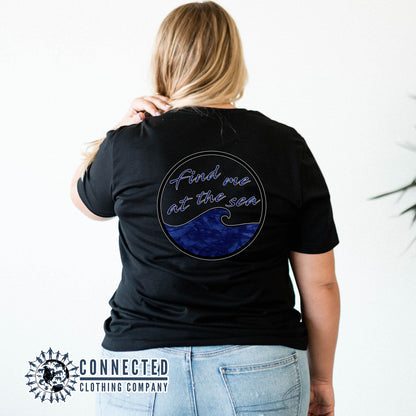 Model Wearing Black Find Me At The Sea Short-Sleeve Tee in front of dock on the water - Connected Clothing Company - 10% donated to Mission Blue ocean conservation