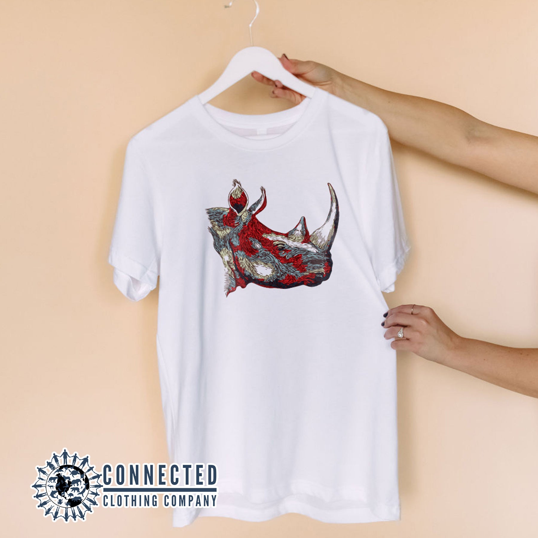 Hands Holding Hanger With  White Vanishing Into Extinction Rhino Tshirt - Connected Clothing Company - Ethically and Sustainable Clothing - 10% of proceeds are donated to rhino conservation